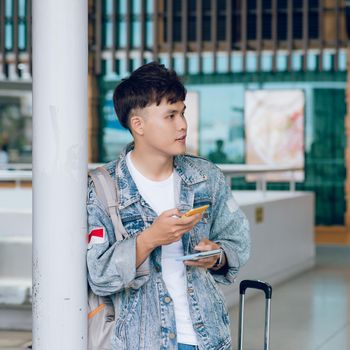 Portrait of smiling man texting while waiting for taxi in the airport