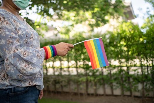 Asian lady holding rainbow color flag, symbol of LGBT pride month celebrate annual in June social of gay, lesbian, bisexual, transgender, human rights.