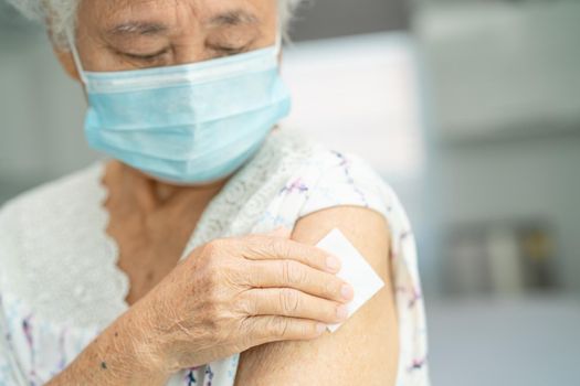 Elderly Asian senior woman wearing face mask getting covid-19 or coronavirus vaccine by doctor make injection.