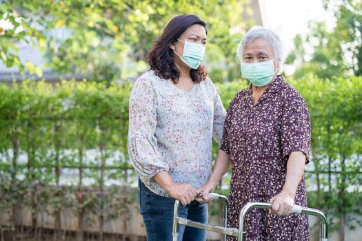 Asian senior or elderly old lady woman walk with walker and wearing a face mask for protect safety infection Covid-19 Coronavirus.