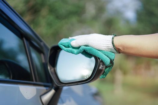 Cleaning car with green color microfiber cloth outdoor in holiday.