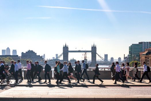 London, England - July 04 2016: Morning commuters in London walking to work across London Bridge with Tower Bridge in the background