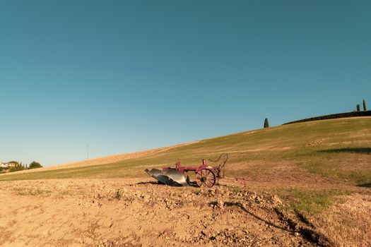 Closeup of a plow standing on a hill in the idyllic Tuscan countryside, Tuscany, Italy.