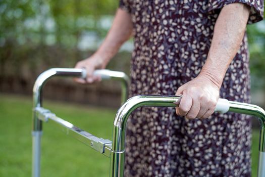 Asian senior or elderly old lady woman patient walk with walker in park, healthy strong medical concept.