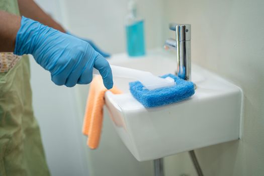 Maid cleaning wash and scrub basin in toilet at home.