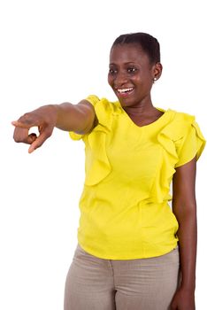 young girl standing in yellow camisole on gray background shows something with laughing finger.