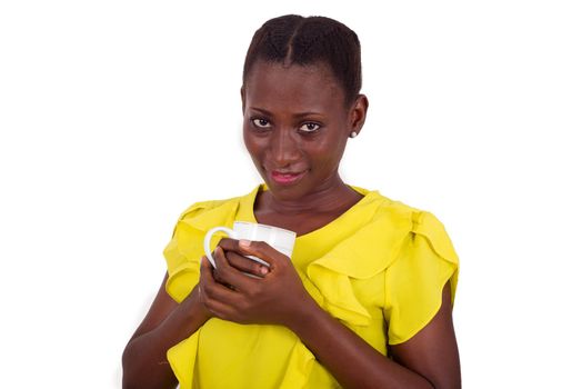 young girl standing in yellow camisole a cup against the chest and looks at the camera smiling.