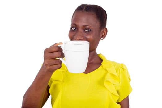 young girl standing in yellow camisole with a cup in hand smiling at the camera.