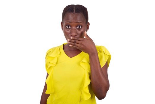 young girl standing in yellow camisole looks at camera with hand on mouth and a surprised air.