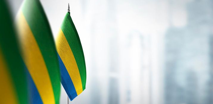 Small flags of Gabon on a blurry background of the city.