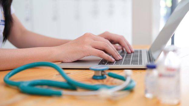 Doctor sitting at workplace and using laptop
