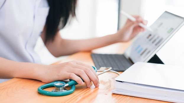 Doctor sitting at workplace and using laptop
