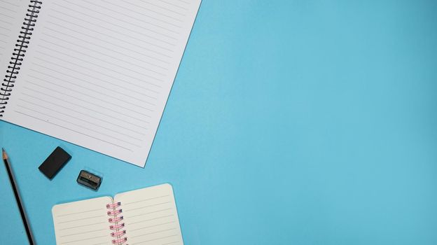 Education or back to school Concept. Top view of Colorful school supplies with books, color pencils, calculator, pen cutter clips and apple on blue pastel background. Flat lay.