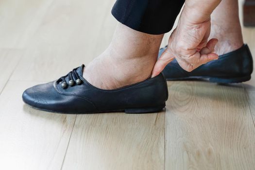 Elderly woman putting on shoes.