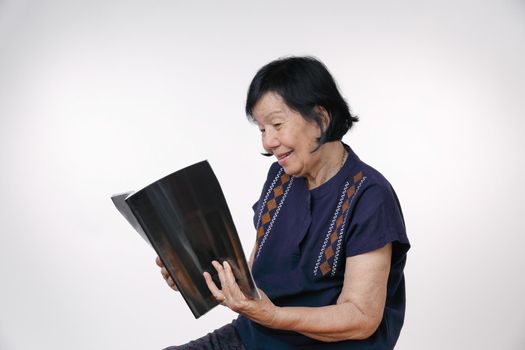 elderly woman reading a magazine on white background