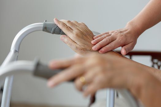 Elderly asian woman using a walker at home with caregiver take care