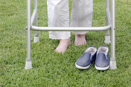 Elderly woman walking barefoot therapy on grass in backyard.