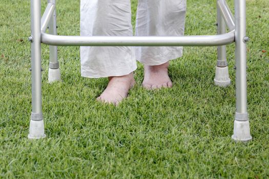 Elderly woman walking barefoot therapy on grass in backyard.
