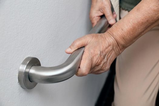 Elderly woman holding on handrail for safety walk steps