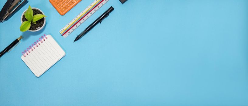 Education or back to school Concept. Top view of Colorful school supplies with books, color pencils, calculator, pen cutter clips and apple on blue pastel background. Flat lay.
