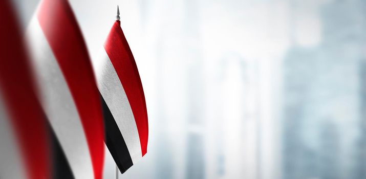 Small flags of Yemen on a blurry background of the city.