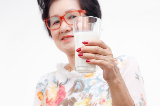 Senior woman holding a glass of milk , isolated on white background.