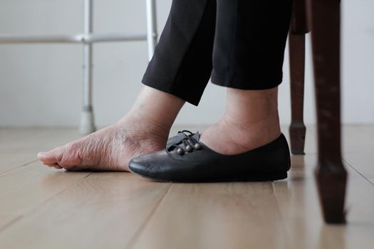 Elderly woman swollen feet putting on shoes