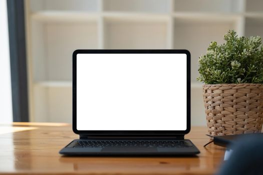 Shot of digital tablet with blank white screen, keyboard, cup of coffee on workspace desk.