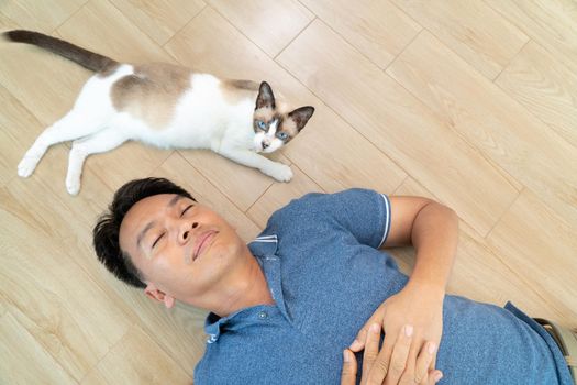 Asian man with elder cat lying on floor at home.