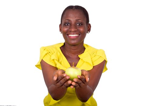 young girl standing in yellow camisole holding an apple in her palms and looking at camera smiling.