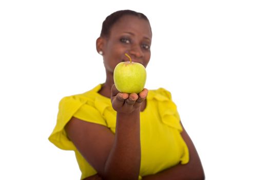 young girl standing in yellow camisole showing an apple smiling at the camera.