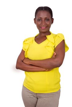 African girl in yellow camisole standing on gray background crossed hands and smiles at the camera.