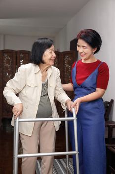 Elderly asian woman using a walker at home with daughter take care