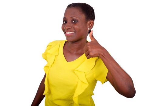 young girl standing in yellow camisole making thumb sign smiling on camera.