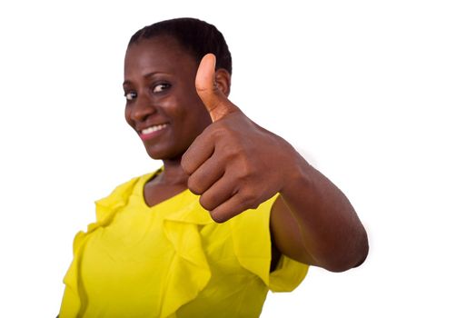 young girl standing in yellow camisole making thumb sign smiling on camera.