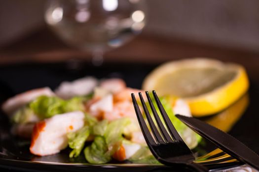 cutlery resting on a plate of fish salad on wooden background