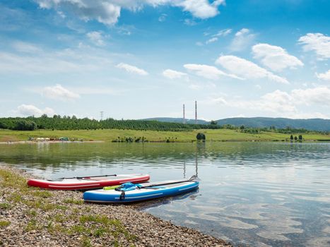 Two colors set of stand up paddleboards on a lake beach. Sport and relax at Milada lake near Usti nad Labem, Czechia.