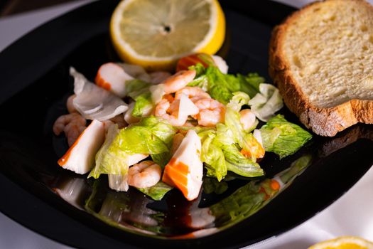 composition of a black plate with shrimp and surimi salad on a white satin background
