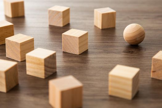 Wooden sphere ball among the wood cubes, different and position in niche market concept