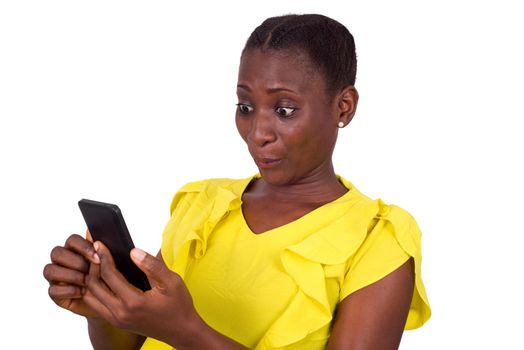 young girl standing in yellow camisole with surprise looks at her mobile phone.