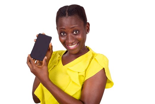young girl standing in yellow camisole shows her mobile phone while smiling at the camera.
