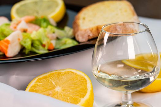 a lemon split in half in front of a plate of fish with a glass of white wine