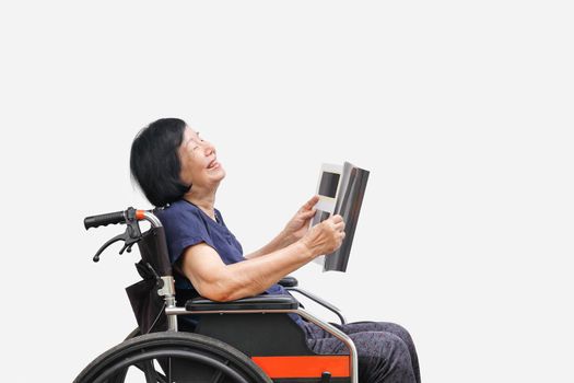 Senior asian woman laughing while reading magazine on white background.