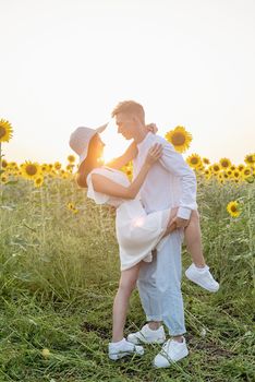 Autumn nature. Young romantic couple walking in sunflower field in sunset