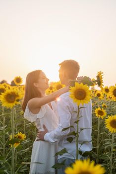 Autumn nature. Love and romance. Young romantic couple hugging in sunflower field in sunset