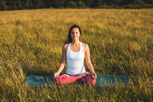 Beautiful woman sitting in lotus position and meditating in the nature,Padmasana/Lotus position.