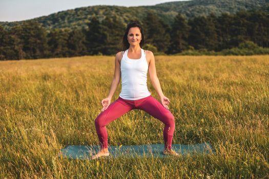 Beautiful woman doing yoga in the nature/Goddess squat pose,Utkata Konasana.