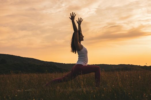 Silhouette of a woman doing yoga in the nature/Virabhadrasana,Warrior pose flow.