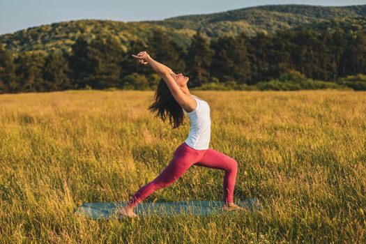 Beautiful woman doing yoga in the nature,Virabhadrasana/Warrior pose.