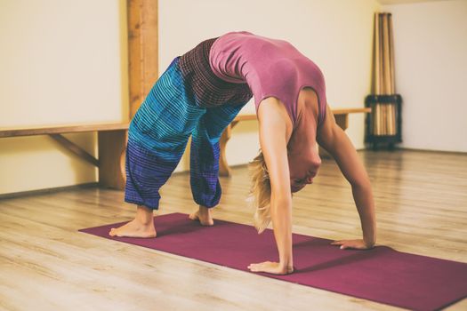 Woman doing yoga Urdhva Dhanurasana/Upward bow pose.Toned image.